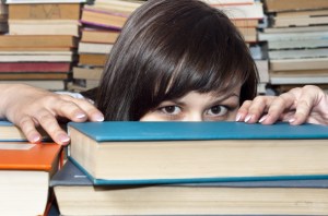 girl hiding behind books